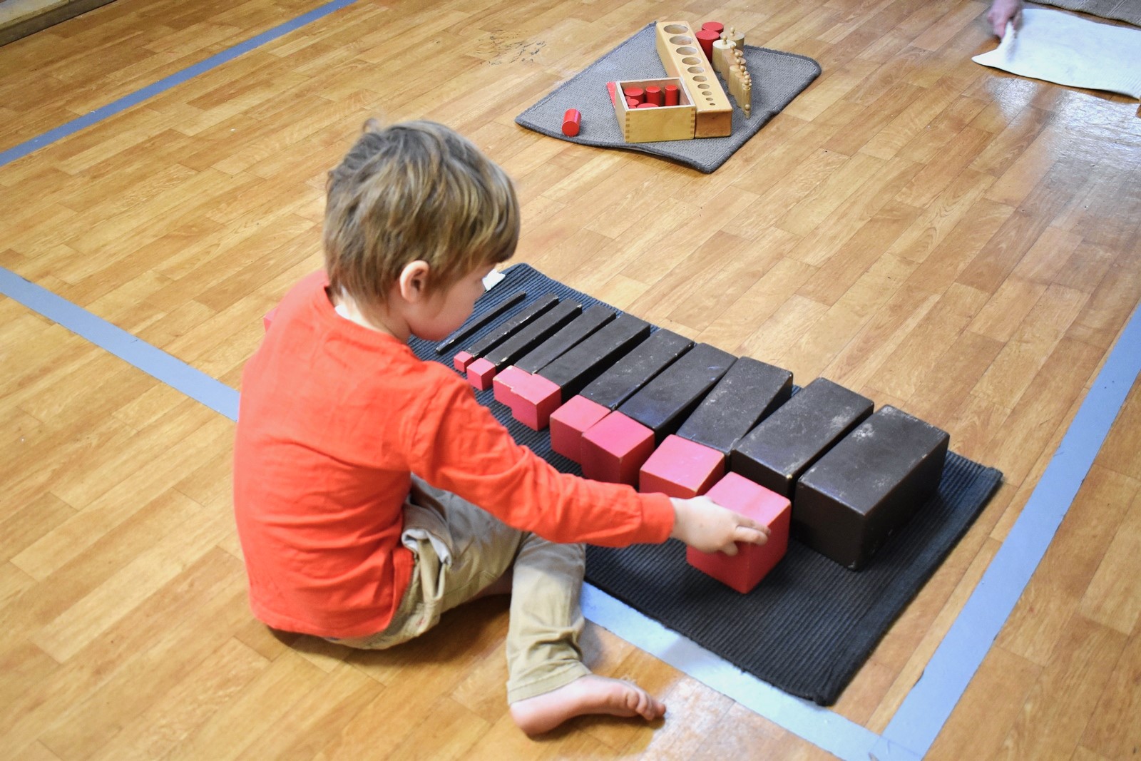 Young boy building with Montessori colour tablets on a mat